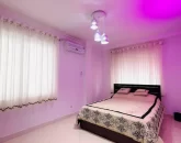 تخت خواب با روتختی سفید مشکی و نور پردازی با رنگ بنفش اتاق خواب ویلا در شیرود