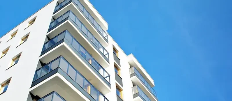 نمای بیرونی سنگی ساختمان با تراس های شیشه ای در زیر آسمان آبی صاف و انتخاب بهترین طبقه آپارتمان برای سکونت 4937584838