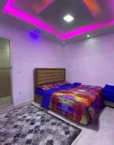 تخت خواب با روتختی رنگی و سقف نور پردازی شده با نور بنفش اتاق خواب خانه روستایی در جواهرده