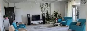 مبلمان کرمی آبی و تلویزیون و گلدان های سرسبز سالن نشیمن آپارتمان در شیرود