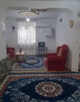 مبلمان قرمز و فرش آبی رنگ سالن نشیمن خانه روستایی در اوشیان